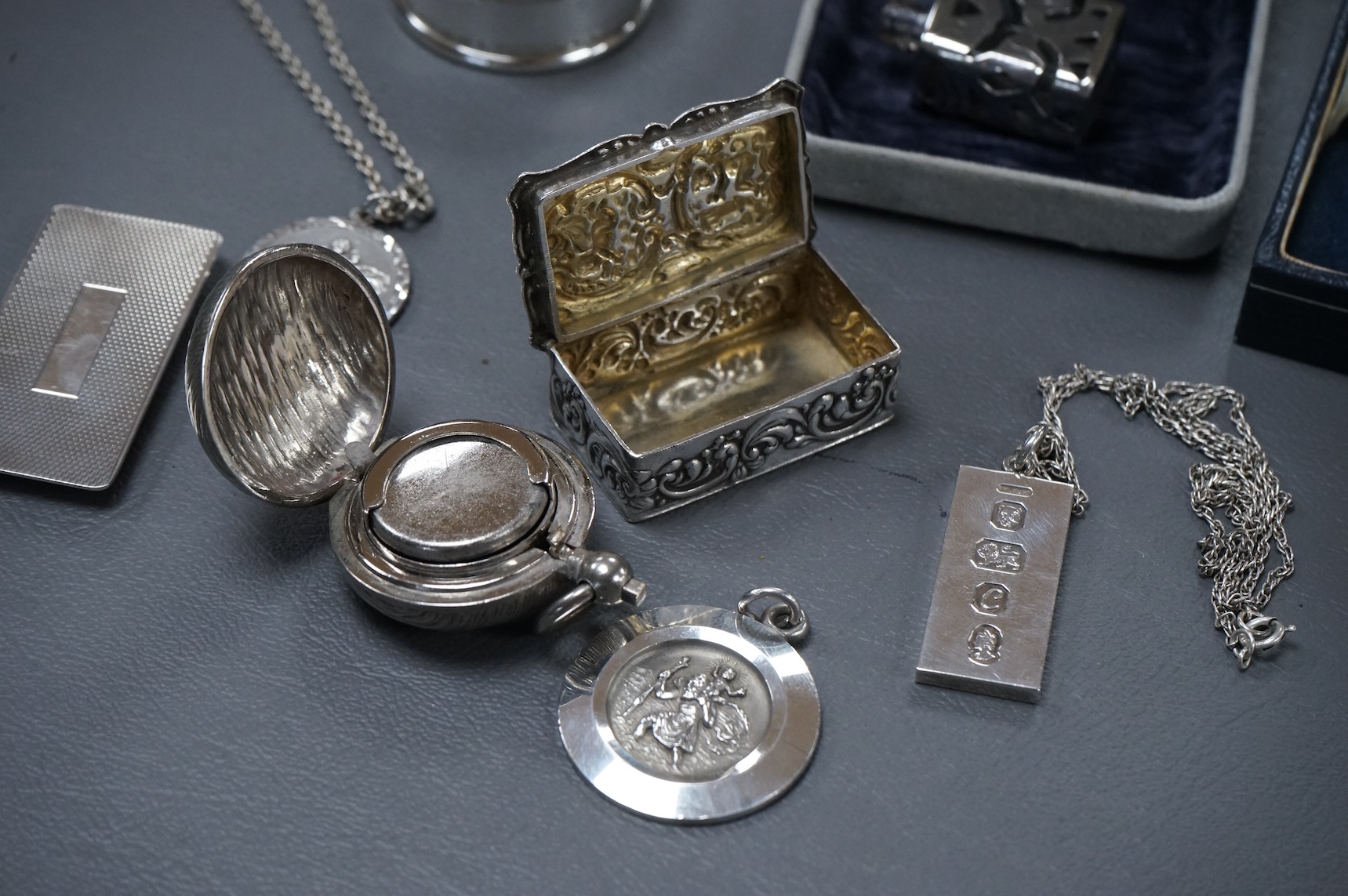 A group of mainly modern silver collectables including three assorted scent flasks and funnels by Ari D. Norman, two money clips, matchbox sleeve, napkin ring, pill box, three pendants including ingot and a pair of Victo